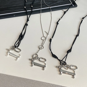 Macro shot of silver dachshund dog pendants with black cord and metal chains on a clean desk