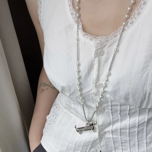 Detail view of long pearl necklace with silver Hector dachshund pendant on model