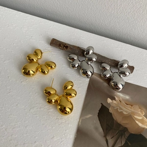 Makroaufnahme abstrakter Metall-Ohrstecker in hochglänzendem Gold- und Silber-Finish