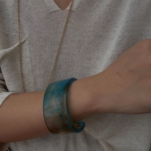Close-up of wide marble textured resin bangle with blue and brown dye-stained effect