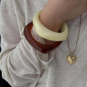 Chunky resin bangle set in cream marble and amber tones worn by a model in soft light