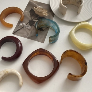 Close-up of colorful marble resin bracelets with crescent shapes on a white ceramic plate