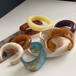 Detailed close-up of wide resin bangles in marble blue, amber, and tortoiseshell patterns