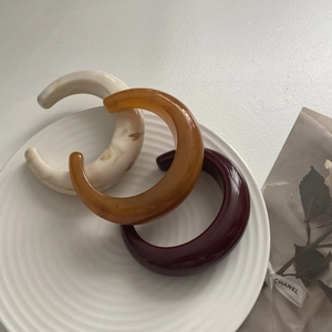 Three-piece set of thick C-shaped resin bangles in marble, amber and burgundy colors