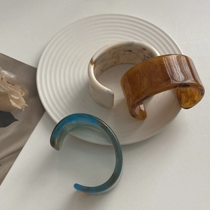 Detail view of colorful resin bangles in marble, amber, and gradient blue styles