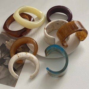 Close-up of chunky resin bangles in marble, tortoiseshell and solid colors on an art book