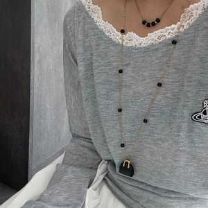 Mehrlagige Goldkette und schwarze Perlenhalskette mit schickem Mini-Handtaschenanhänger