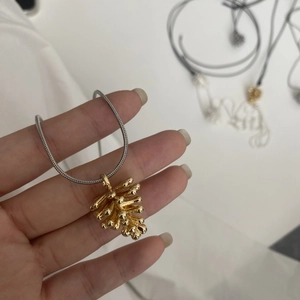 Primer plano de un colgante de piña dorada en una cadena de serpiente plateada flexible