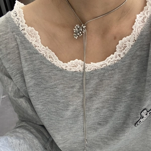 Collar con colgante de piña plateado y borla sobre un jersey con encaje gris