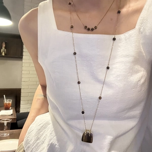 Detail von geschichteten Tigerauge-Halsketten mit Mini-Handtaschen-Anhänger auf Weiß