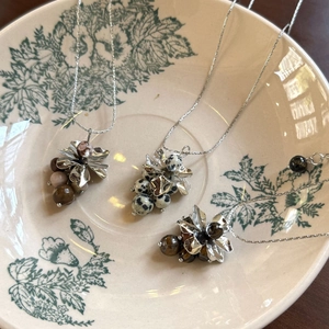 Detail view of retro grape-shaped pendants with natural stones on a vintage floral plate