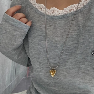 Primer plano de un colgante de piña dorada con cadena larga de plata usado por una modelo