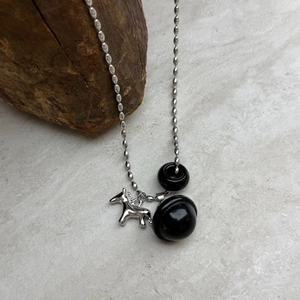 Dettaglio della collana con catena a sfere argentata con perle nere e ciondolo a cavallo