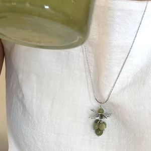 Close-up of green natural stone grape pendant necklace on a delicate silver chain