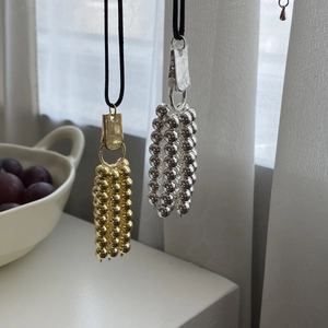 Detailweergave van lange parelketting met gouden kwastjes en verstelbaar zwart koord