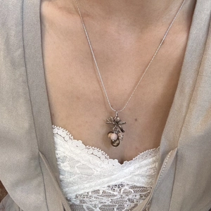 Detail view of floral necklace with natural stones on model wearing lace and cardigan