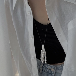 Detail van parelkwastje met zwart koord gedragen op een linnen shirt model