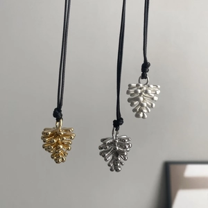 Detalle de colgantes de piña en oro y plata con cordón negro ajustable para mujer