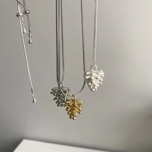 Detalle de los colgantes de piña en plata y oro con cadena de metal ajustable de calidad