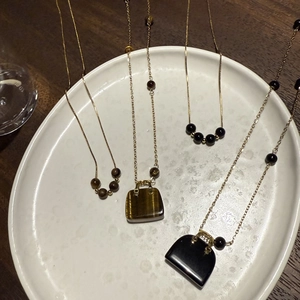 Detailansicht von Tigerauge und Obsidian Mini-Taschen-Anhängern an goldener Halskette