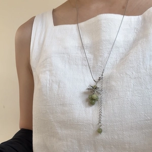 Detail of green natural stone grape pendant necklace with silver chain on model