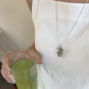 Detail of green stone grape pendant necklace with silver chain on model in linen dress