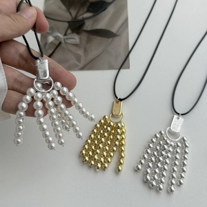 Detail van de lange parel- en metalen kralenkwastketting met verstelbaar koord