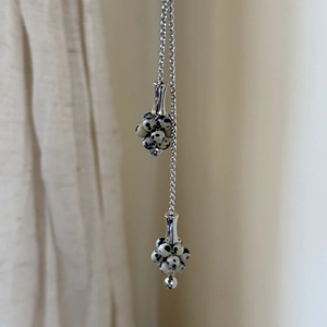 Macro detail of silver necklace featuring spotted natural stone beads in a cluster pendant
