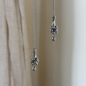 Detail einer silbernen langen Kette mit runden Perlenanhängern und Quasten-Design