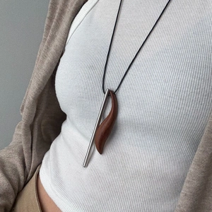 Detail view of long minimalist necklace with ebony wood pendant on a model's sweater