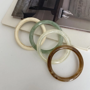 Set of four irregular resin bangles in beige, green, and amber colors with glossy finish