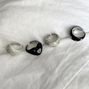 Detail of adjustable black and cream heart rings with cubic zirconia on white cloth