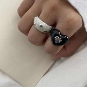 Detailed macro view of beige marbled ring with silver hearts and black zircon heart ring
