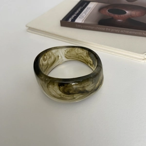 Close-up of olive green ink-wash resin bangle with artistic marbling and smooth texture