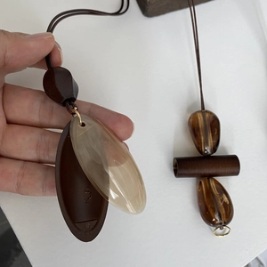 Detailed view of Maillard brown resin pendants and leaf-shaped charms on long necklaces