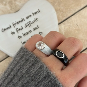 Detail showing two thick rings with black and marble enamel and inlaid cubic zirconia