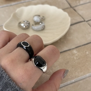 Detail shot of hand wearing black enamel rings with an irregular aesthetic shape