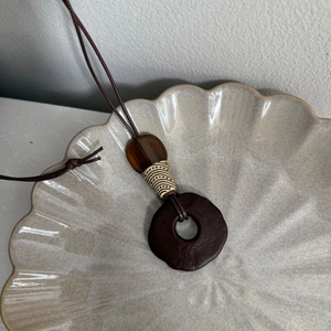 Detail of bohemian brown tassel necklace with spiral beads and amber stone pendant