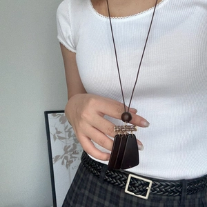 Detail of a Maillard brown wooden tassel necklace on a white knitted sweater