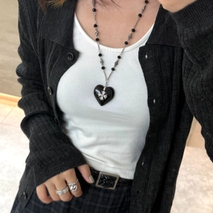 Close-up of gothic black heart pendant necklace with silver cross on a female model