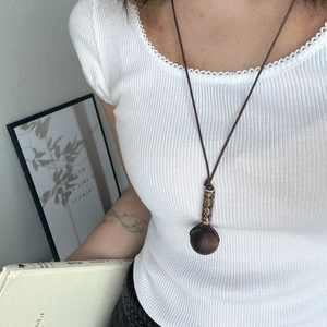 Close-up of a brown resin ball pendant with intricate hand-woven tassels on long rope