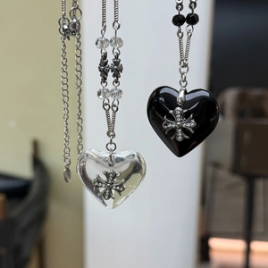 Close-up of black and transparent heart pendants with silver cross on metallic chains