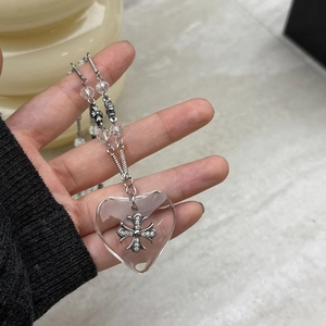 Close-up of heart pendant with silver cross and crystal beads on a metallic chain