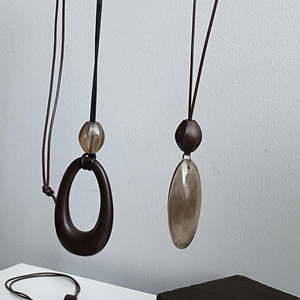 Detail view of ethnic resin pendants in amber and brown on minimalist wax cords