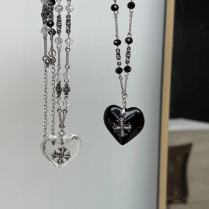 Detail of gothic heart pendants with silver cross pattern on metal beaded chains
