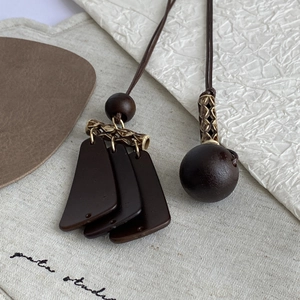 Detailed macro view of vintage Maillard brown pendant necklace with tassel and wooden beads
