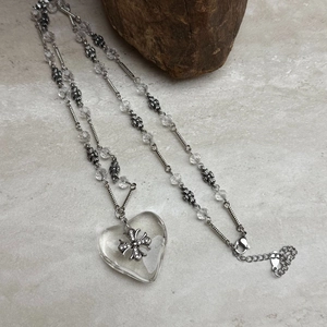 Macro detail of transparent heart pendant with crystal cross on vintage silver chain