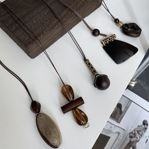Close-up of bohemian brown resin pendant necklaces with wood beads on a dark wood background