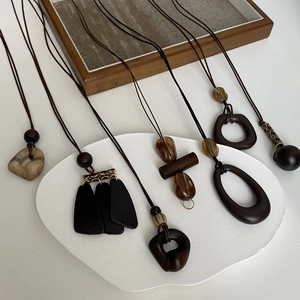 Detailed view of six ethnic long necklaces featuring wood, resin, and stone pendants