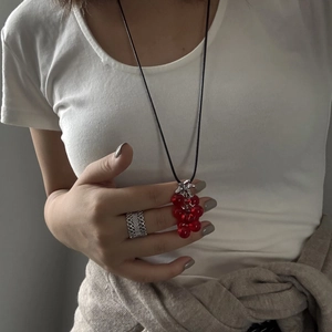 Close-up of a grape cluster pendant on a black cord with a textured silver ring